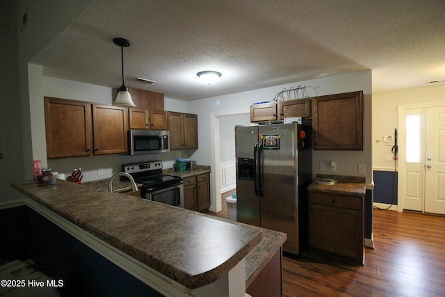 2208 Sweet Bay Dr Unit A, Greenville, NC 27834 - kitchen with appliances with stainless steel finishes, dark countertops, a textured ceiling, a peninsula, and dark wood-style flooring