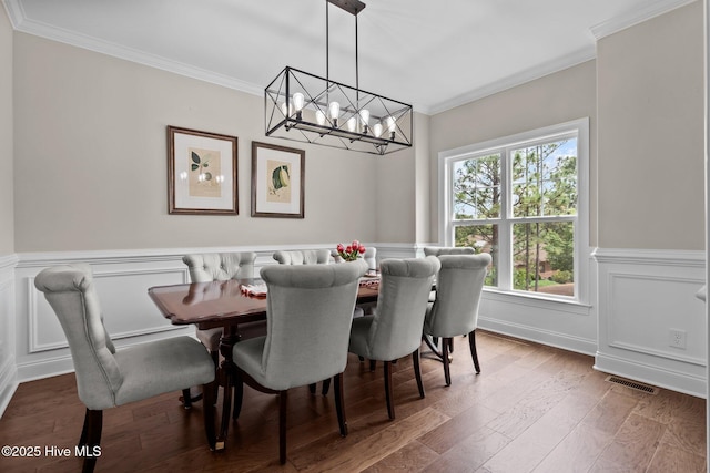 125 Steeplechase Way, Southern Pines, NC 28387 - dining room with ornamental molding, a chandelier, wainscoting, wood finished floors, and a decorative wall