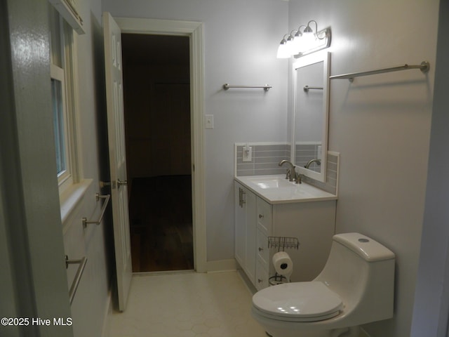 bathroom with toilet, vanity, and tasteful backsplash