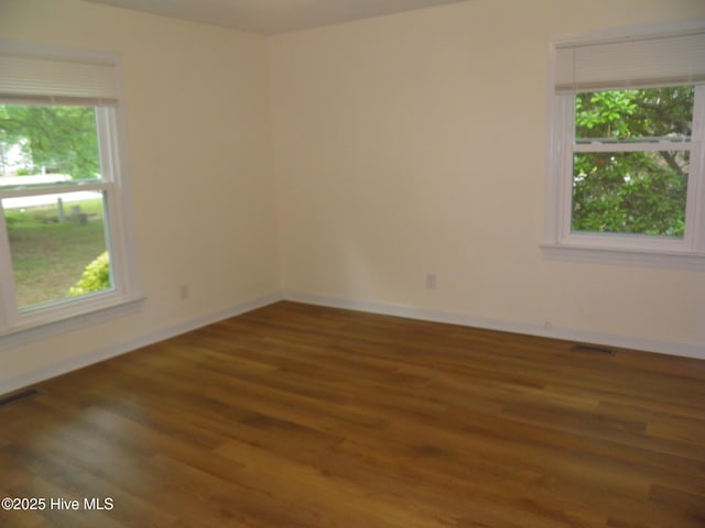 unfurnished room with wood finished floors, healthy amount of natural light, and baseboards