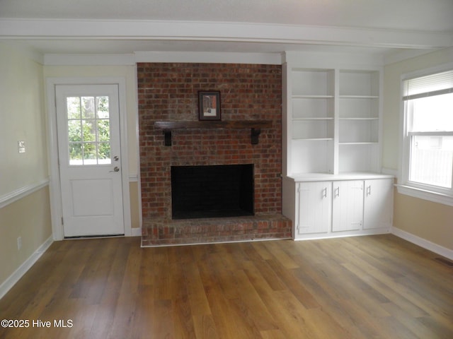 unfurnished living room featuring healthy amount of natural light, wood finished floors, baseboards, and a fireplace
