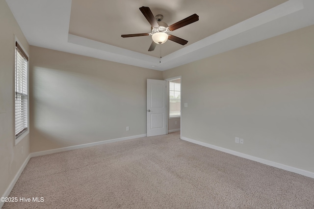1232 Teakwood Dr, Greenville, NC 27834 - spare room featuring a tray ceiling, ceiling fan, baseboards, and light colored carpet