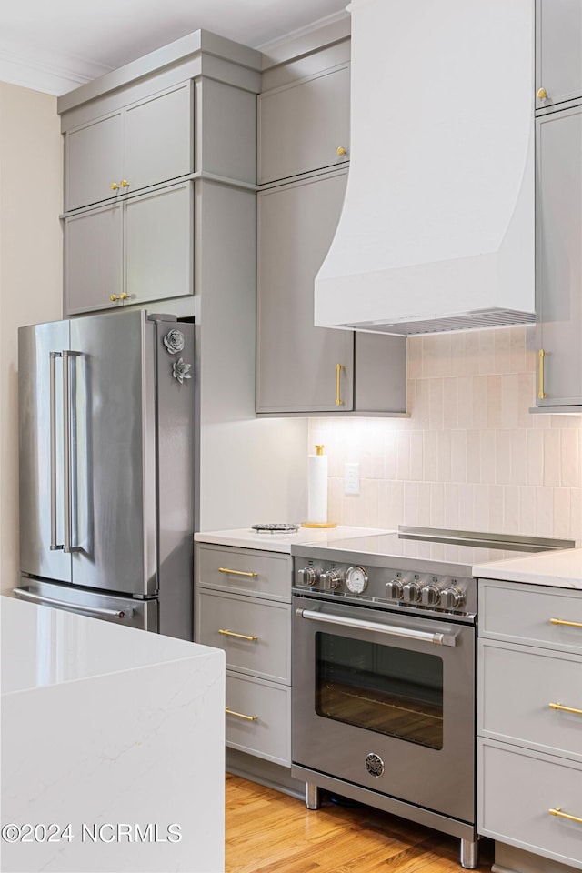 6920 Runningbrook Ter, Wilmington, NC 28411 - kitchen with high quality appliances, gray cabinets, premium range hood, light countertops, and decorative backsplash