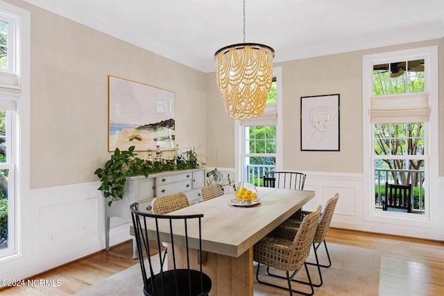 6920 Runningbrook Ter, Wilmington, NC 28411 - dining area featuring a chandelier, light wood-type flooring, a wainscoted wall, crown molding, and a decorative wall