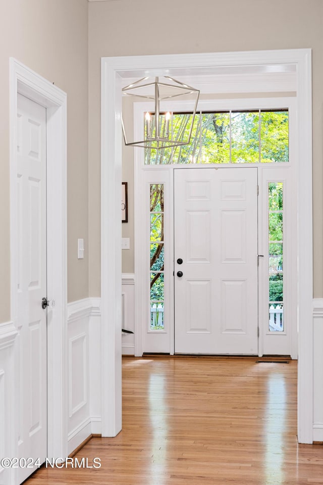 6920 Runningbrook Ter, Wilmington, NC 28411 - entryway with a chandelier, light wood-type flooring, a decorative wall, and wainscoting