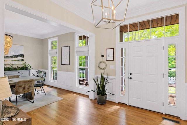 6920 Runningbrook Ter, Wilmington, NC 28411 - foyer with a chandelier, crown molding, light wood-style flooring, wainscoting, and a decorative wall