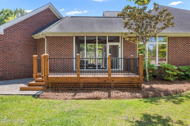 6920 Runningbrook Ter, Wilmington, NC 28411 - rear view of house featuring a sunroom, a wooden deck, a lawn, and brick siding