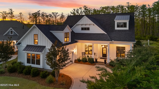view of front facade with covered porch, a standing seam roof, concrete driveway, board and batten siding, and a shingled roof
