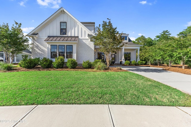 view of front facade with a standing seam roof, a front yard, metal roof, concrete driveway, and board and batten siding