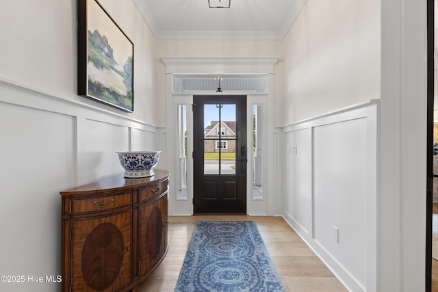entrance foyer featuring a decorative wall, light wood-style flooring, a wainscoted wall, and crown molding