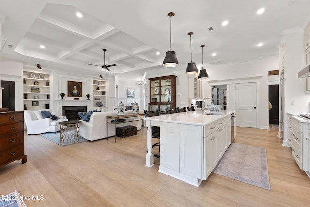 kitchen with a ceiling fan, crown molding, white cabinets, light countertops, and a kitchen bar