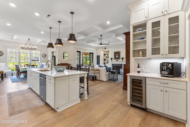 kitchen with wine cooler, open floor plan, a sink, ceiling fan, and beamed ceiling