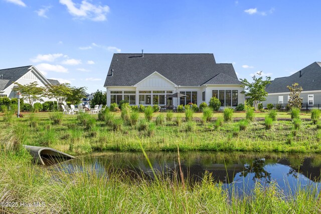 back of house with roof with shingles and a water view