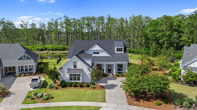 view of front of home featuring board and batten siding, concrete driveway, a standing seam roof, and a front yard