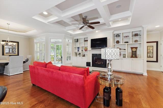 living area with crown molding, a glass covered fireplace, wood finished floors, coffered ceiling, and beamed ceiling