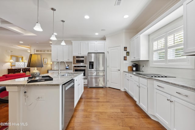 kitchen featuring stainless steel appliances, a sink, white cabinetry, decorative backsplash, and pendant lighting