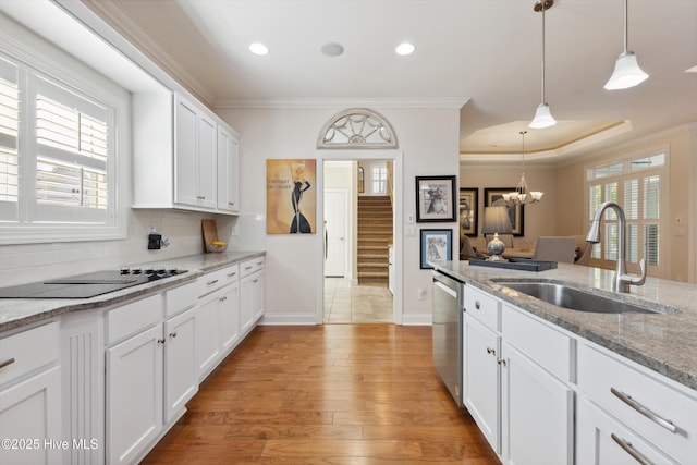 kitchen with stainless steel dishwasher, a sink, black electric stovetop, white cabinetry, and ornamental molding