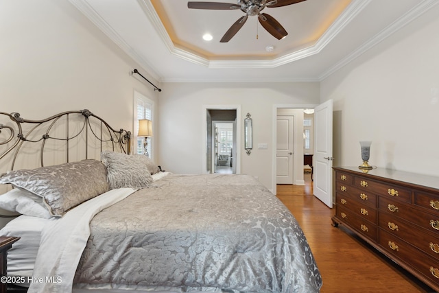 bedroom with a raised ceiling, wood finished floors, ornamental molding, and ceiling fan