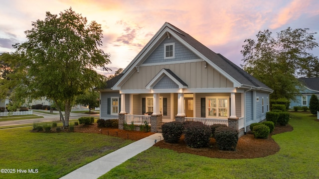 craftsman-style home with covered porch, board and batten siding, and a yard