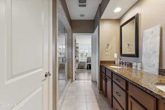 full bathroom featuring tile patterned flooring, double vanity, and a shower stall