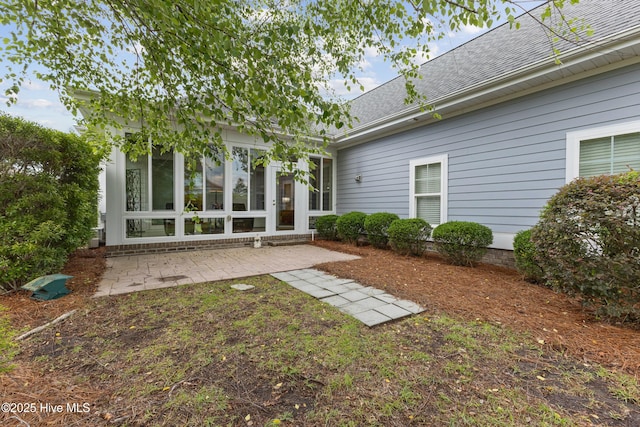 rear view of house featuring a patio and roof with shingles