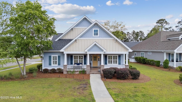 craftsman-style home featuring board and batten siding, a porch, a front lawn, and a shingled roof