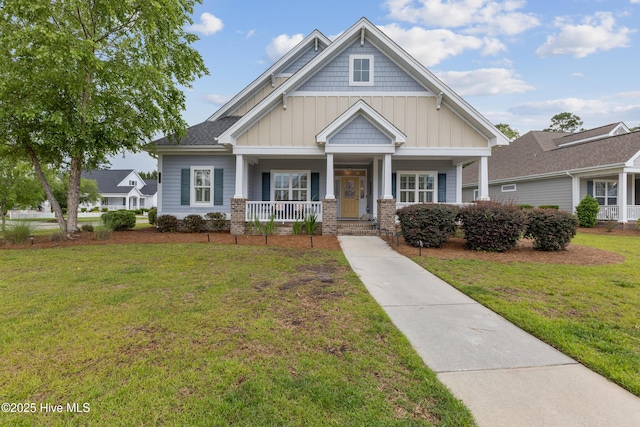 craftsman house featuring board and batten siding, covered porch, and a front lawn