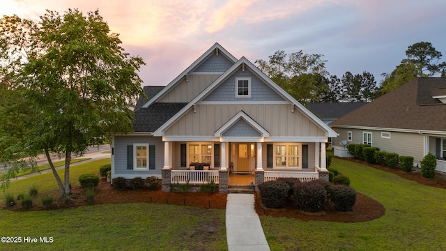 craftsman house featuring board and batten siding, covered porch, and a lawn