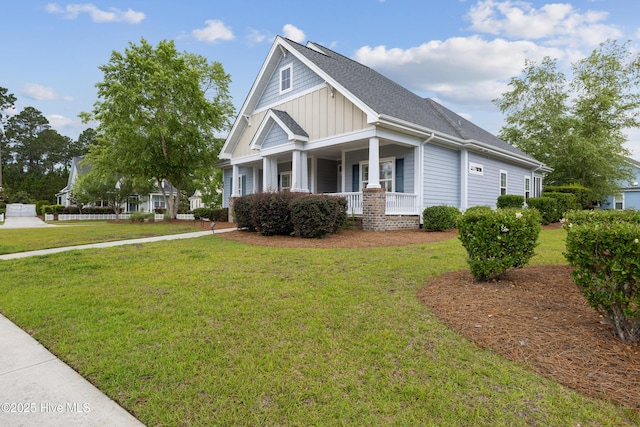 view of front facade with a porch, a front lawn, roof with shingles, and board and batten siding