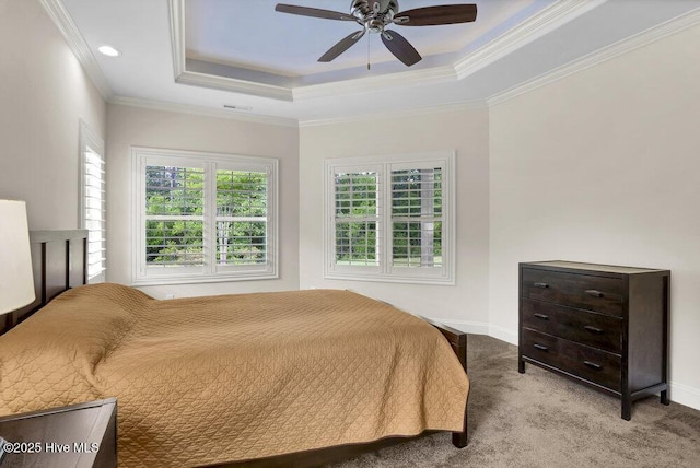 carpeted bedroom with a raised ceiling, baseboards, a ceiling fan, and ornamental molding