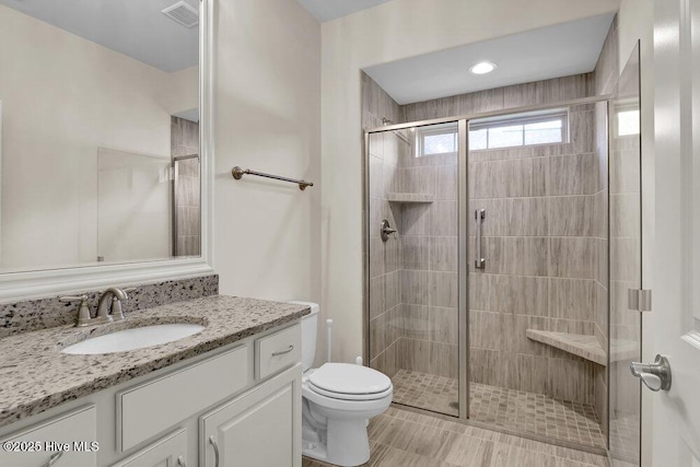 bathroom featuring a stall shower, toilet, and vanity