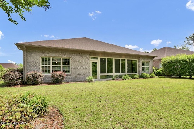rear view of property featuring a yard and brick siding