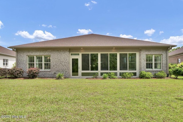 rear view of property featuring a yard and brick siding