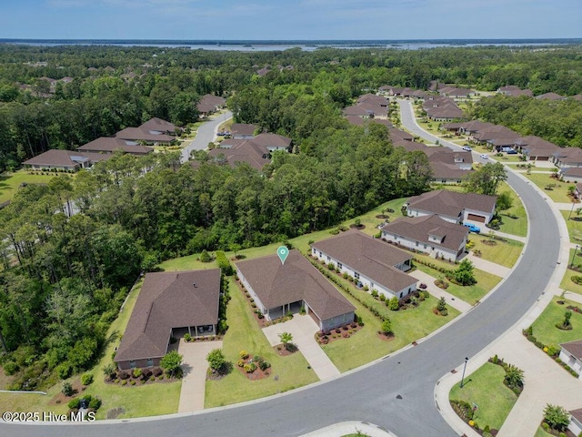 view of property location with nearby suburban area and a forest