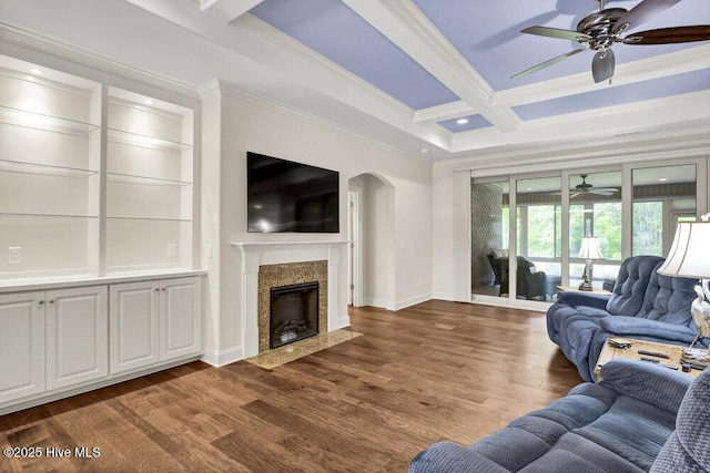 living area with a ceiling fan, ornamental molding, arched walkways, coffered ceiling, and baseboards