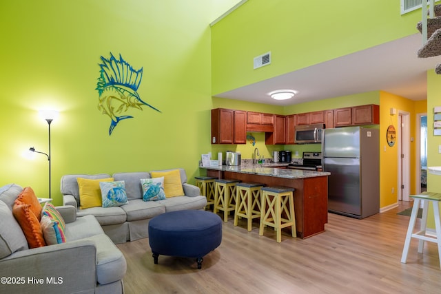 living area featuring light wood-style floors, a high ceiling, and baseboards