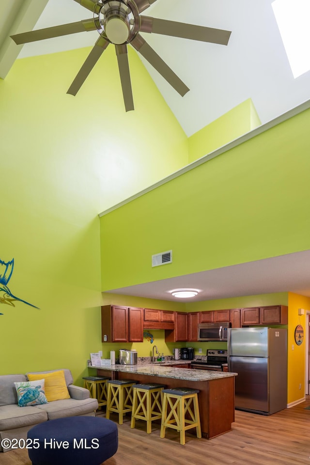 living room featuring high vaulted ceiling, wood finished floors, and a ceiling fan