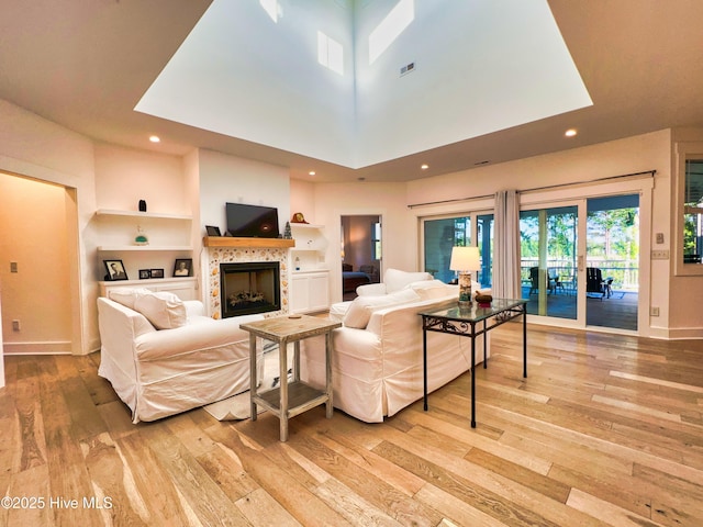 living area featuring light wood-style floors, a tiled fireplace, baseboards, and recessed lighting