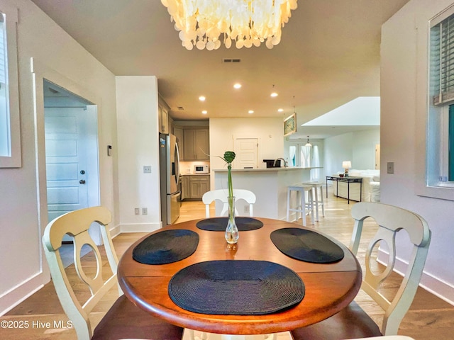 dining area with baseboards, light wood finished floors, a chandelier, and recessed lighting