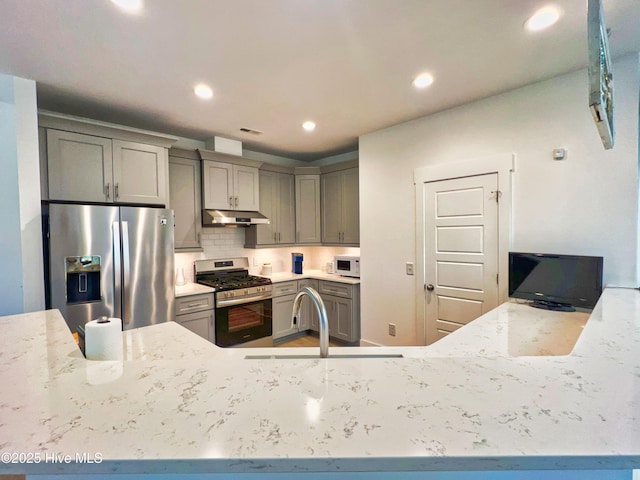 kitchen with appliances with stainless steel finishes, a sink, gray cabinets, under cabinet range hood, and recessed lighting