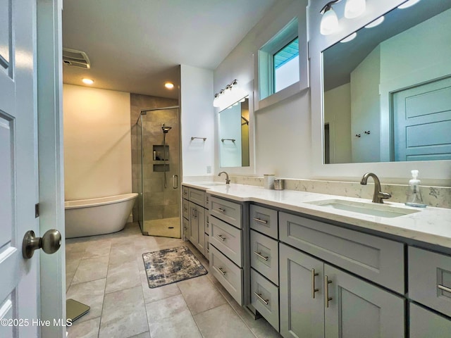 full bathroom featuring a shower stall, double vanity, a freestanding tub, recessed lighting, and tile patterned floors