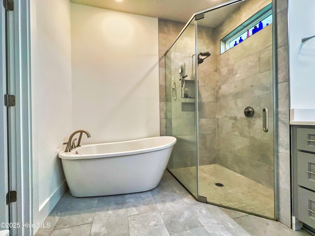 bathroom with a shower stall, a freestanding tub, and baseboards