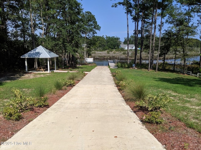 view of community featuring a gazebo, concrete driveway, a yard, and a water view