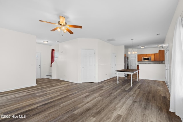 unfurnished living room with ceiling fan, dark wood-type flooring, a chandelier, and baseboards