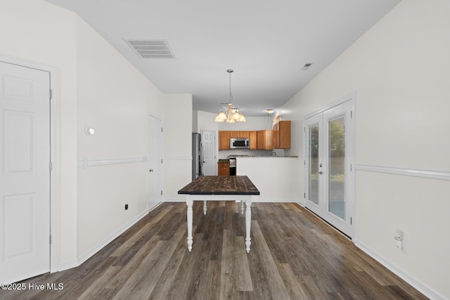 unfurnished dining area with a chandelier, dark wood-type flooring, and baseboards