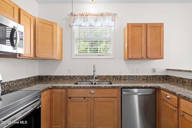 kitchen featuring stainless steel appliances, a sink, and dark stone counters