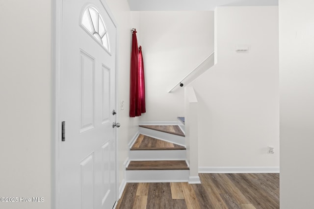 entryway featuring wood finished floors, baseboards, and stairs