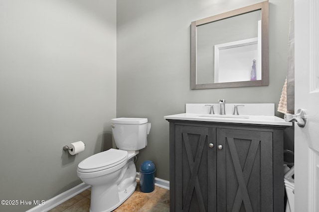 bathroom featuring toilet, vanity, and baseboards