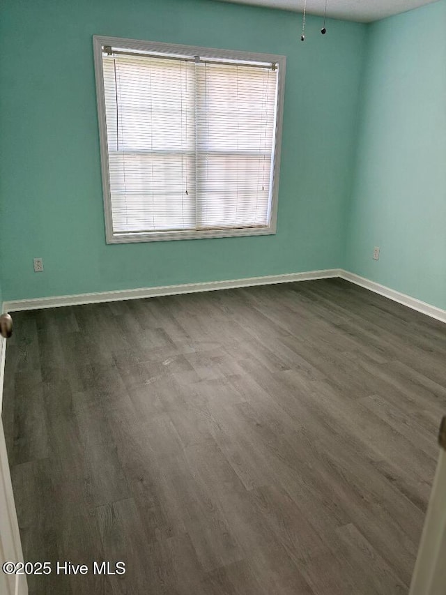 spare room with plenty of natural light, dark wood-style flooring, and baseboards
