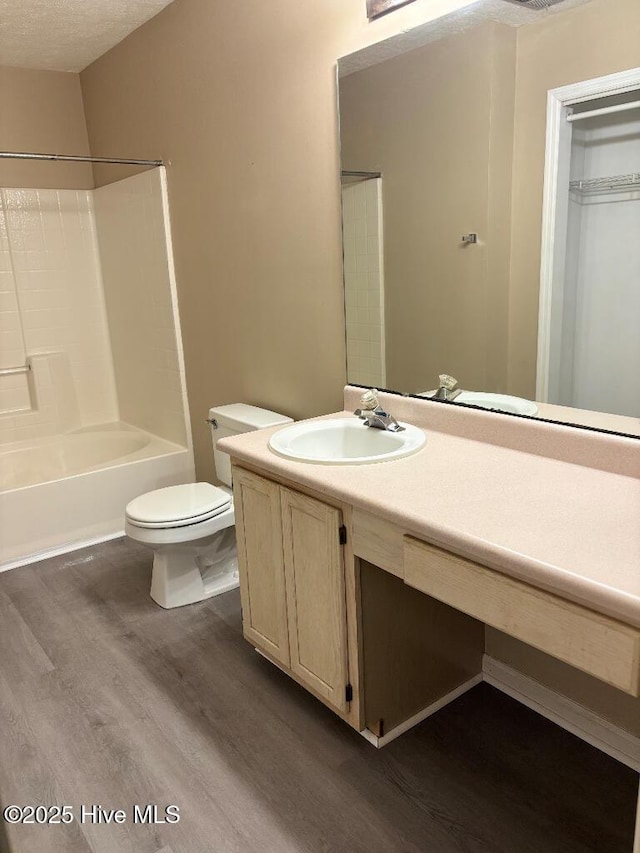 bathroom featuring wood finished floors, toilet, vanity, and shower / bath combination